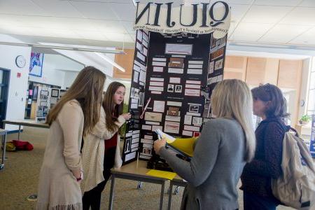 Several students show their exhibit board to onlookers.